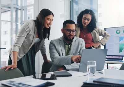 Office workers gather around a computer to consider what LMS to purchase