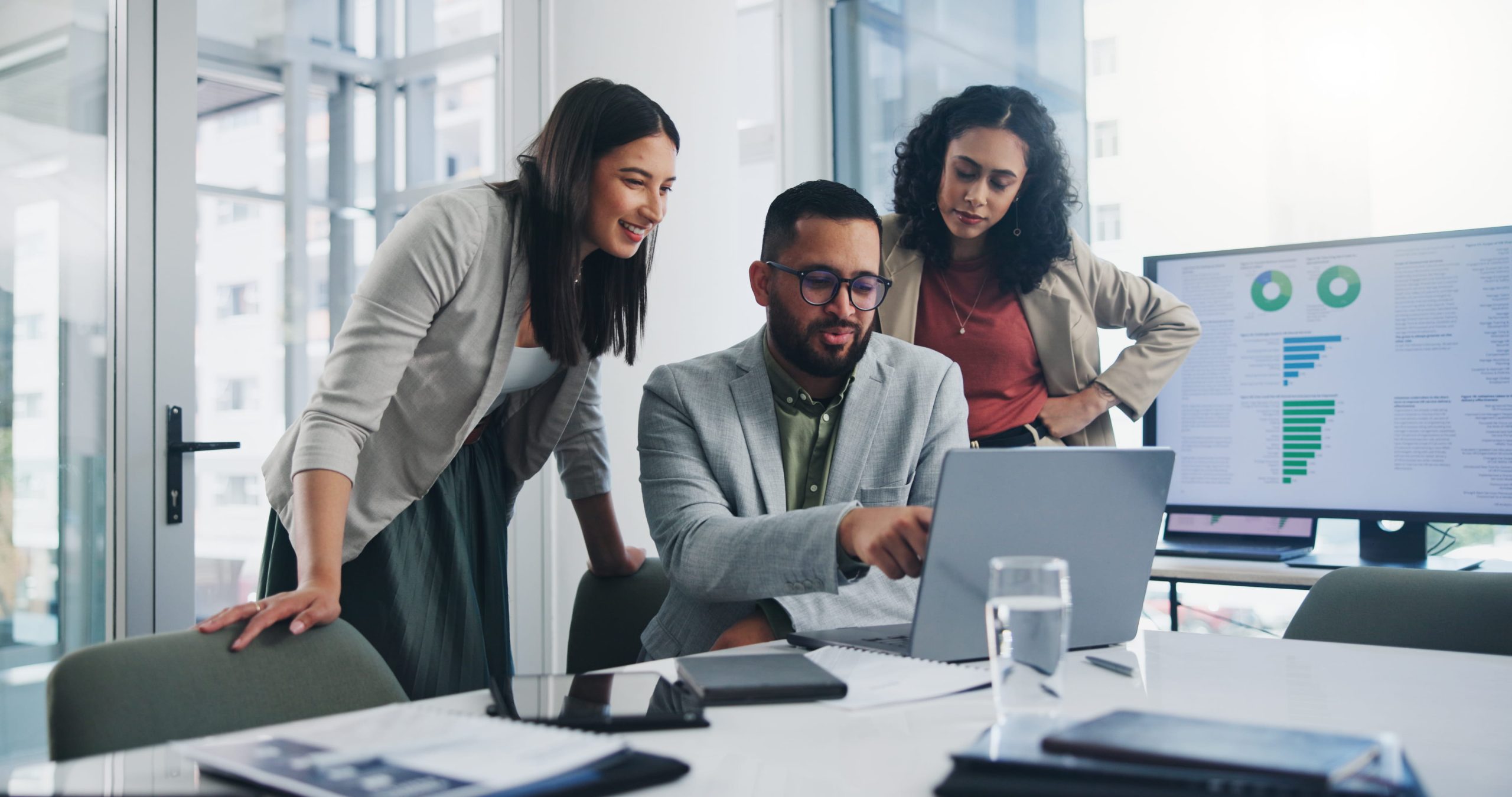 Office workers gather around a computer to consider what LMS to purchase