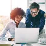 Happy people around computer looking at top EdTech companies